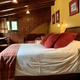 Bedroom king size bed wooden walls Hotel Aran la Abuela Vielha